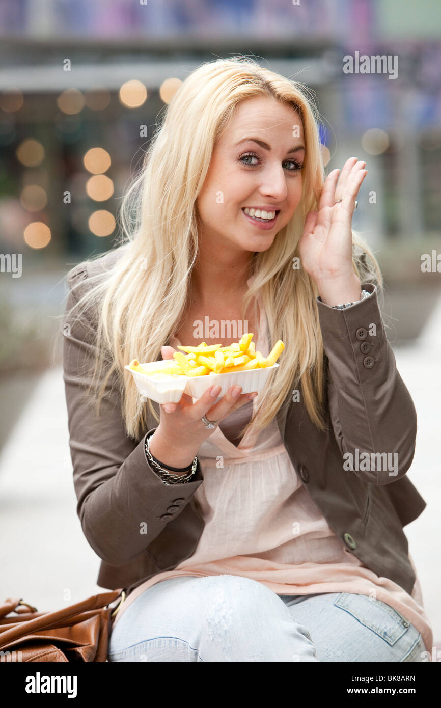 Schöne junge Mädchen mit Pommes frites, die zeigen, dass sie es mag Stockfoto