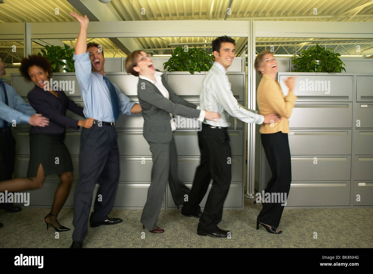Mitarbeiter im Büro tun die Polonaise tanzen Stockfoto