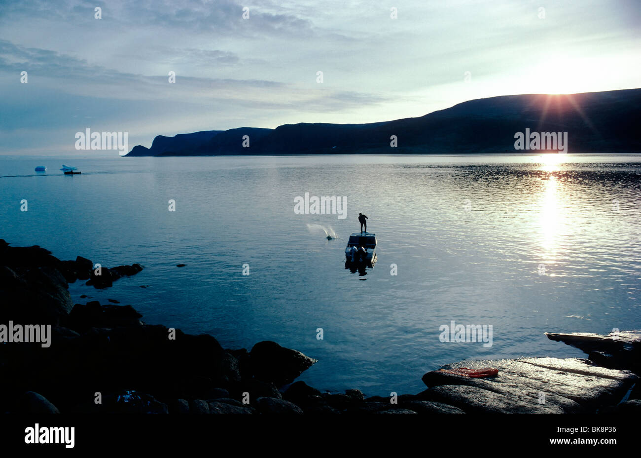 Inuit Fischer wirft ein Netz in den Hafen der kleinen arktische Dorf von E240px, Baffininsel, Nunavut, Kanada Stockfoto