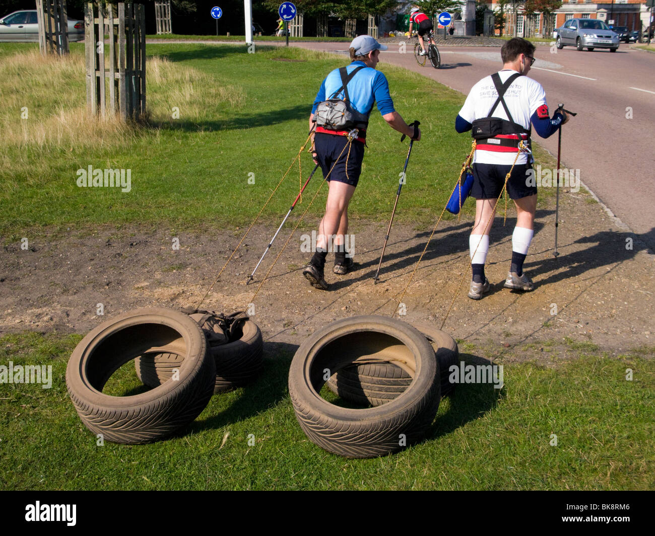 Zwei Männer Fitness training / Ausübung durch Ziehen der Reifen beim Nordic walking. Richmond Park. Richmond. London. VEREINIGTES KÖNIGREICH. Stockfoto