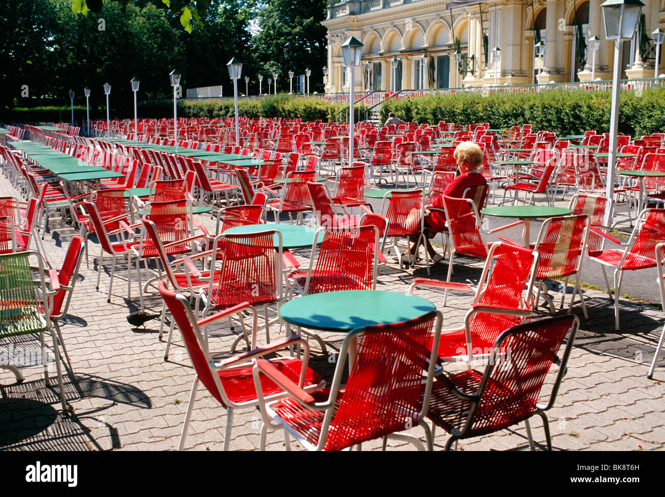Einsame Frau trägt einen roten Pullover sitzen in einem Straßencafé roten Stuhl, Bundesgarten, Burggarten, Hofburg, Wien, Österreich Stockfoto