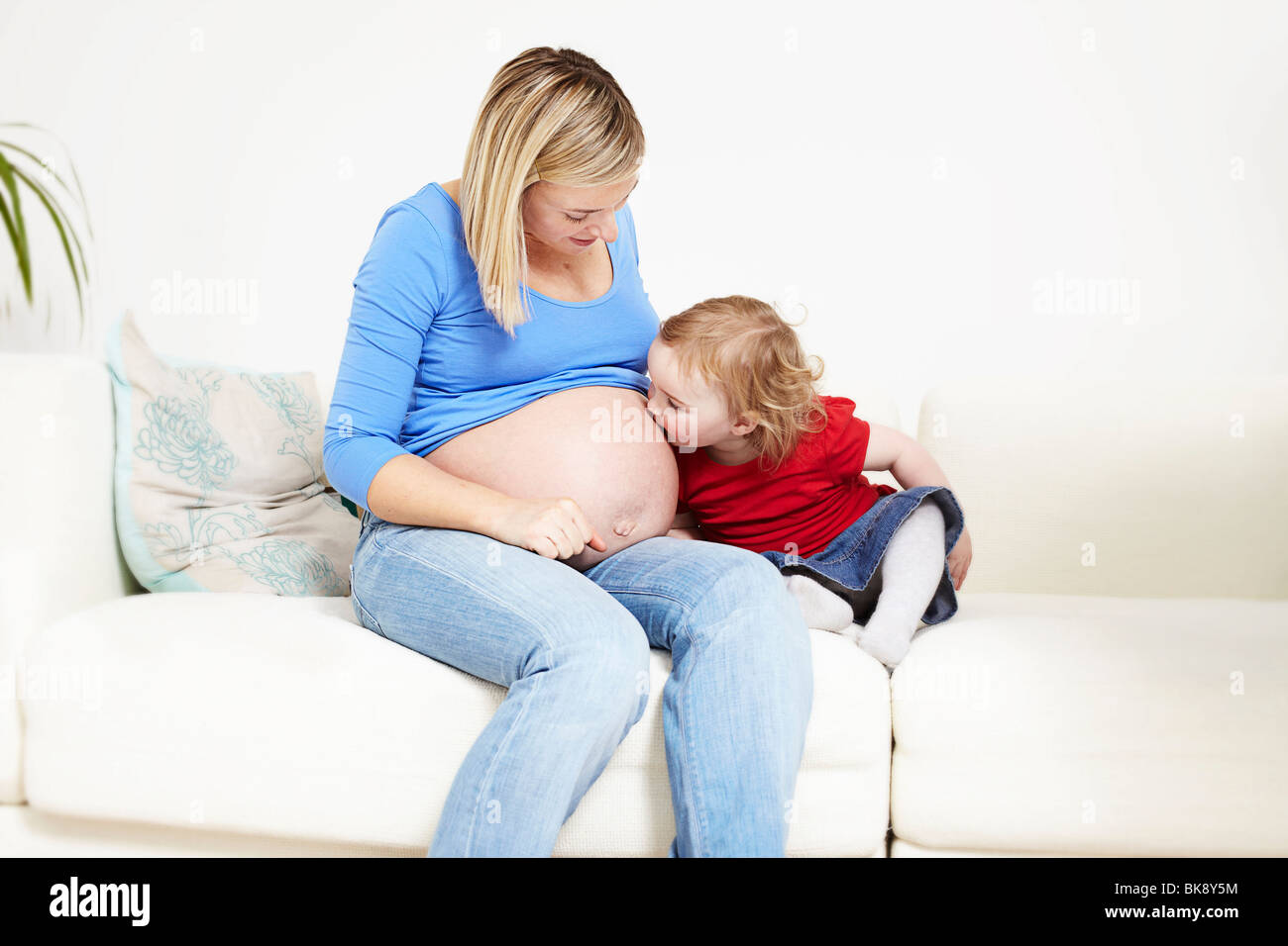 Kleinkind küssen schwangeren Bauch Stockfoto