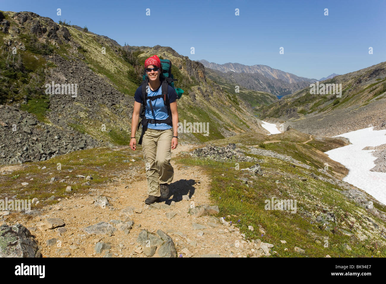 Junge Frau, Wandern, Wandern, Wanderer mit Rucksack, historische Chilkoot Pass, Chilkoot Trail, Schneefeld hinter alpine Tundra, Stockfoto