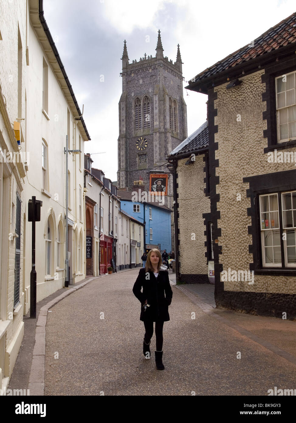 Eine junge Frau, die entlang einer schmalen Straße (Hauptstraße) in der Altstadt in Cromer North Norfolk Stockfoto