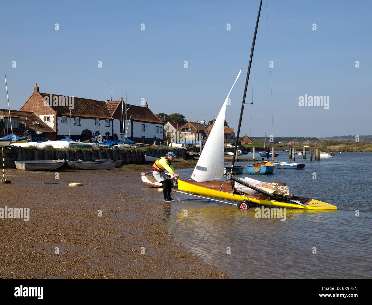Junge männliche Matrose an Burnham Overy Staithe Norfolk eine gelben Jolle aus dem Wasser ziehen Stockfoto