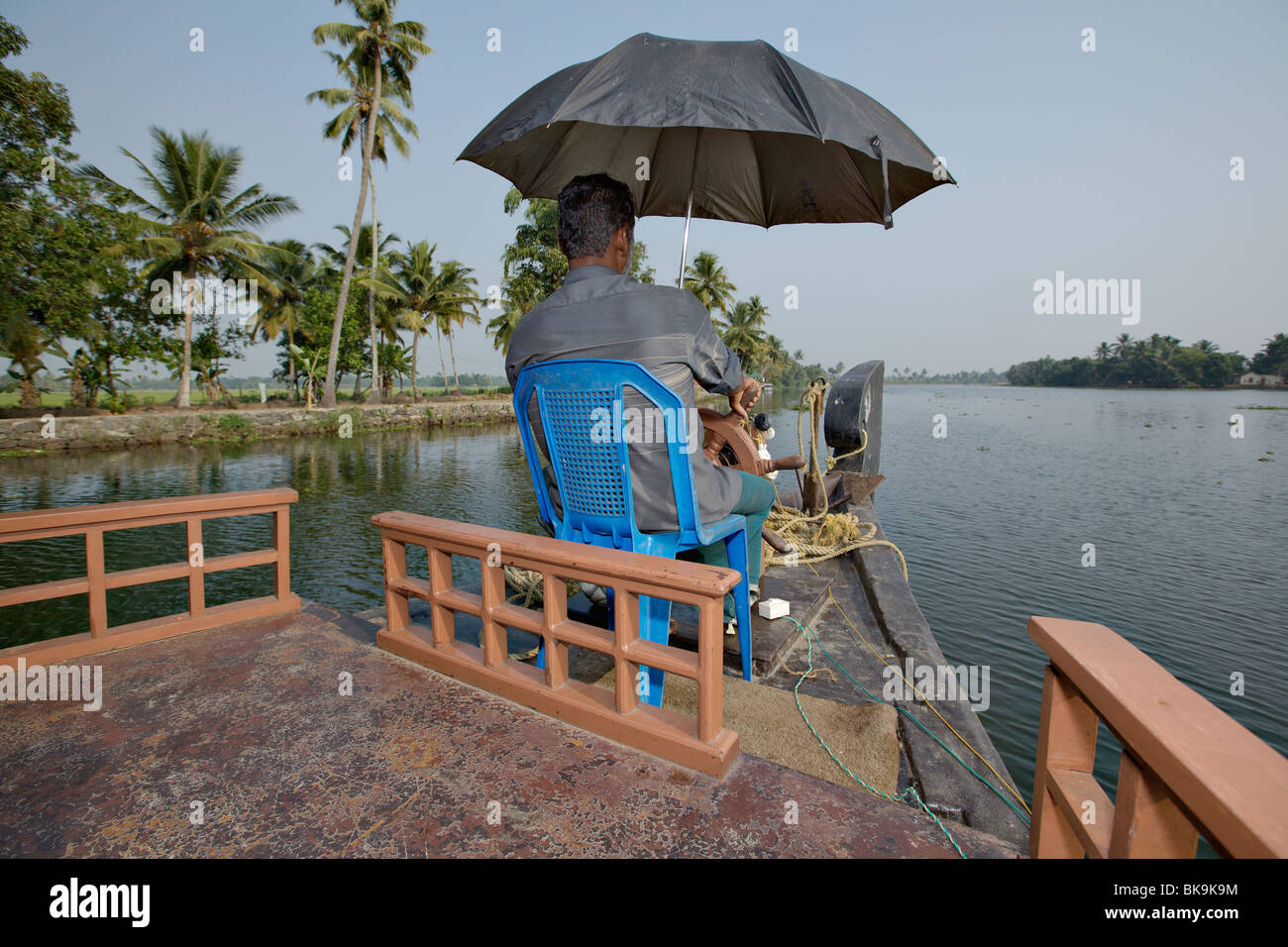 Hausboot-Kapitän Lenkung sein traditionelles Kettuvallam Boot in Backwaters von Kerala, Indien. Stockfoto