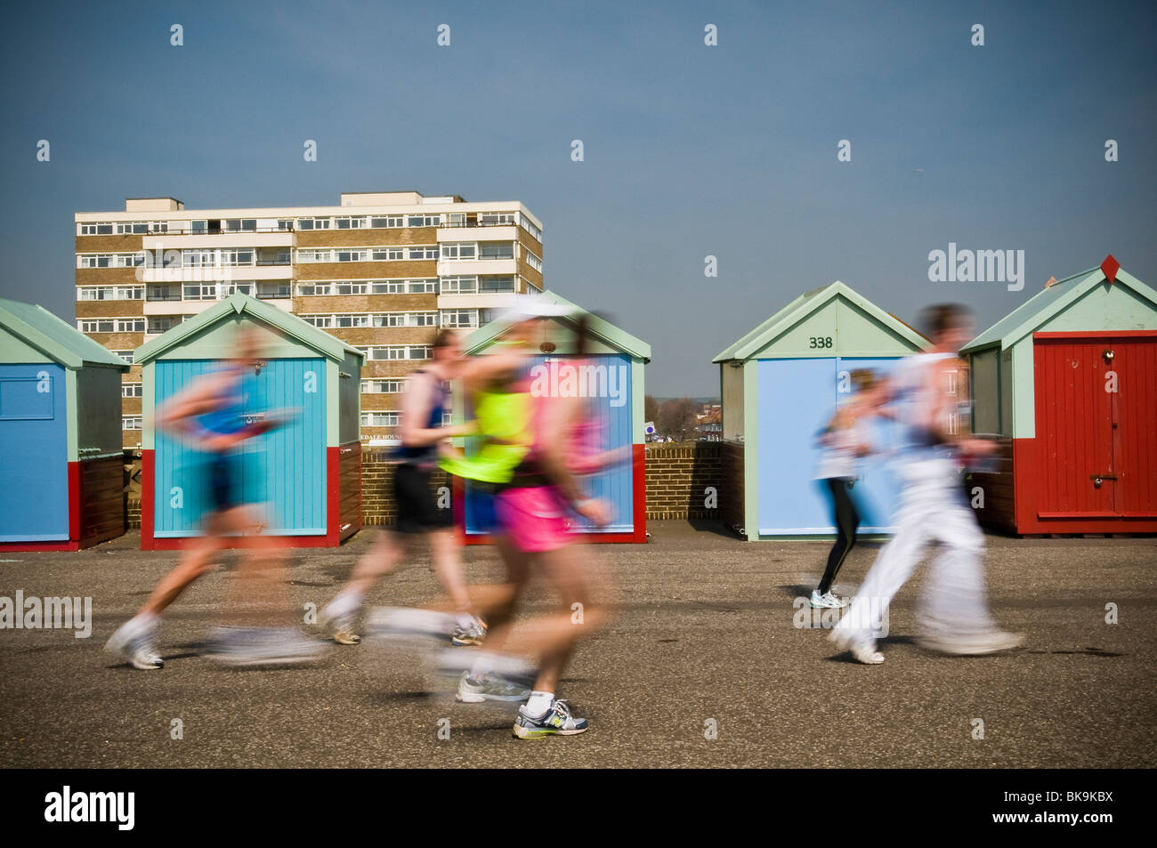 Verschwommene Läufer laufen vorbei an Strandhütten in der ersten Brighton Marathon April 2010, Hove, East Sussex, UK Stockfoto
