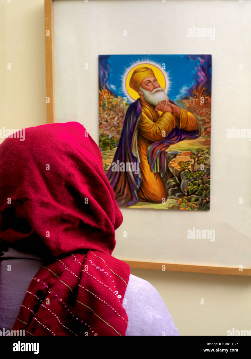 Sikh Frau vor Bild von Guru Nanak Stockfoto
