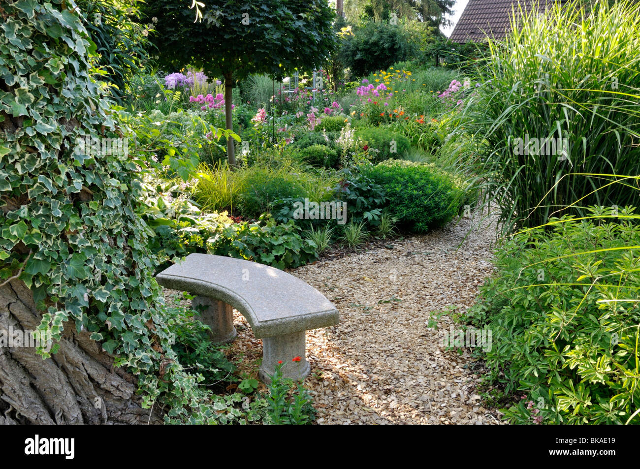 Kleine Steinbank in einem beständigen Garten. Design: Marianne und Detlef lüdke Stockfoto