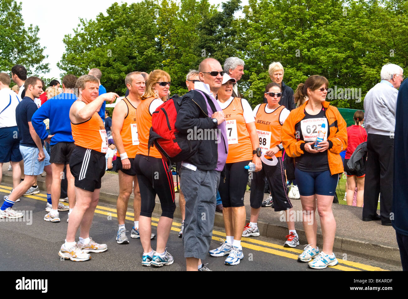 Gruppe von Läufern sammeln in der Straße vor dem Beginn einer 10 km Charity Run suchen nach etwas in der Ferne mit ihren 10k-Nummern angezeigt. Stockfoto