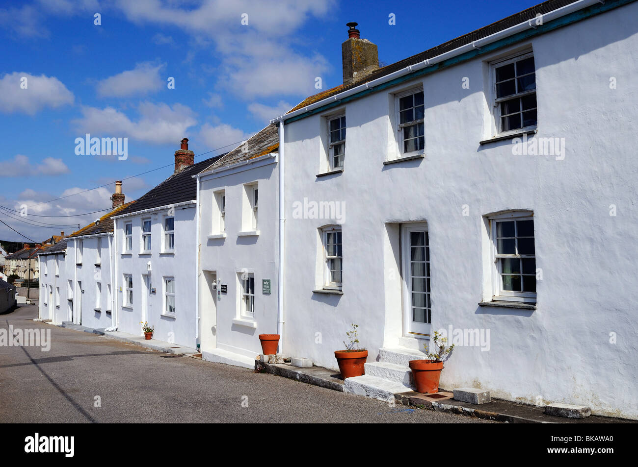 eine Reihe von weißen Häuschen am Hafendamm in Cornwall, Großbritannien Stockfoto