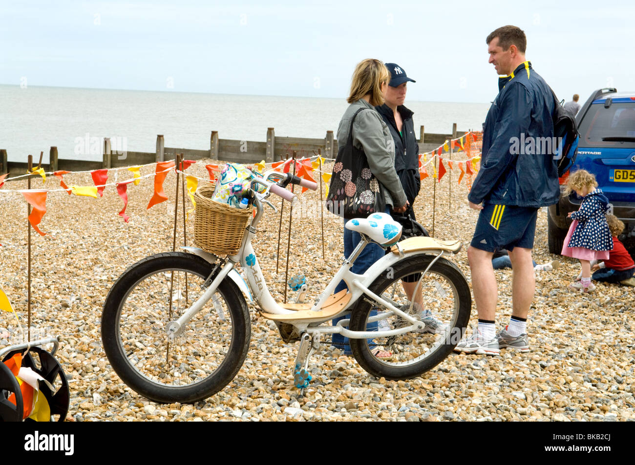 Ziemlich blau flower power Frauen Zyklus auf dem Bike stehen am Strand geparkt mit drei Menschen sprechen von der Seite Stockfoto