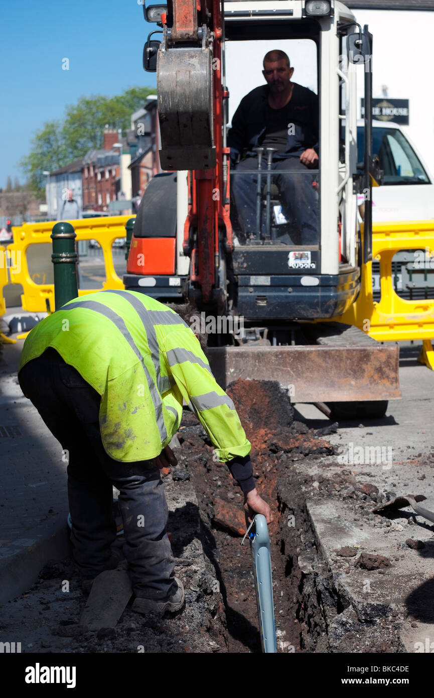 Arbeiter mit einer Kabel-Locater u-Bahn erkennen, dass sein Kumpel in der Minibagger nicht, Service, Großbritannien abgeschnitten. Stockfoto