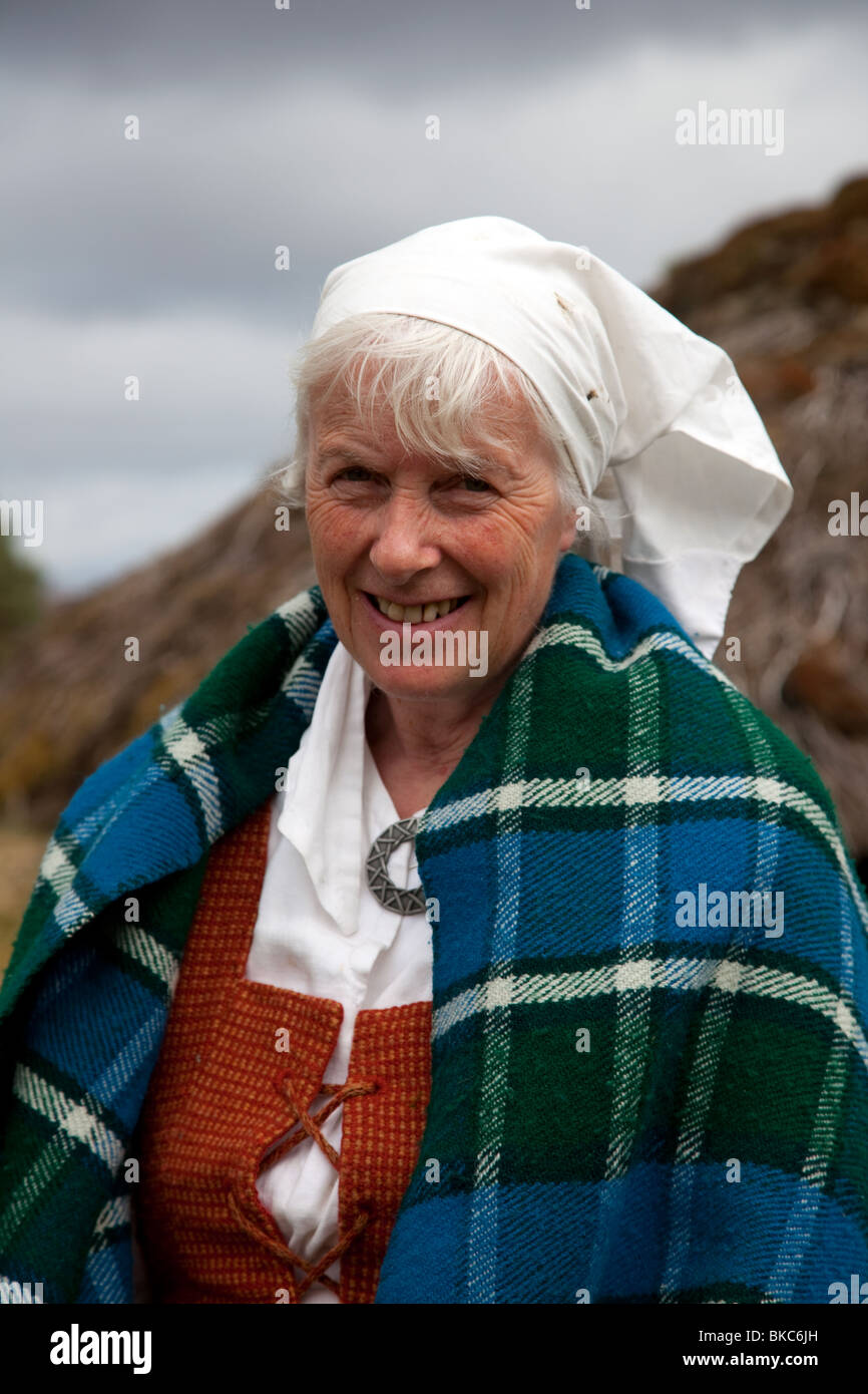 Frau in traditioneller Kleidung, und strohgedeckten Schottischen croft bei Highland Folk Museum, Sehenswürdigkeit in Aviemore, Highlands, Schottland, Großbritannien Stockfoto