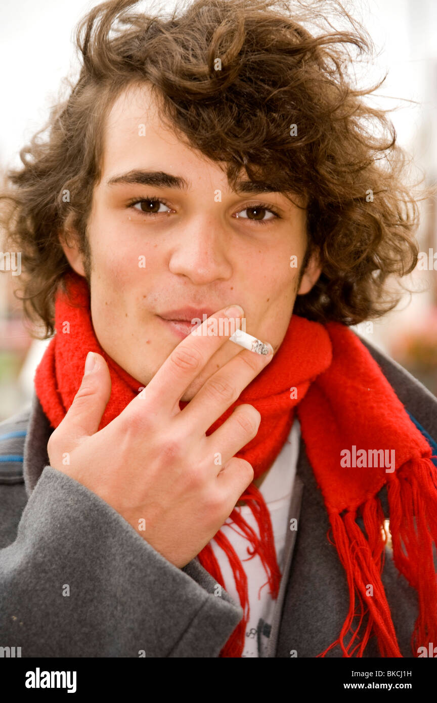 gut aussehende junge Blick in die Kamera, eine Zigarette rauchend Stockfoto