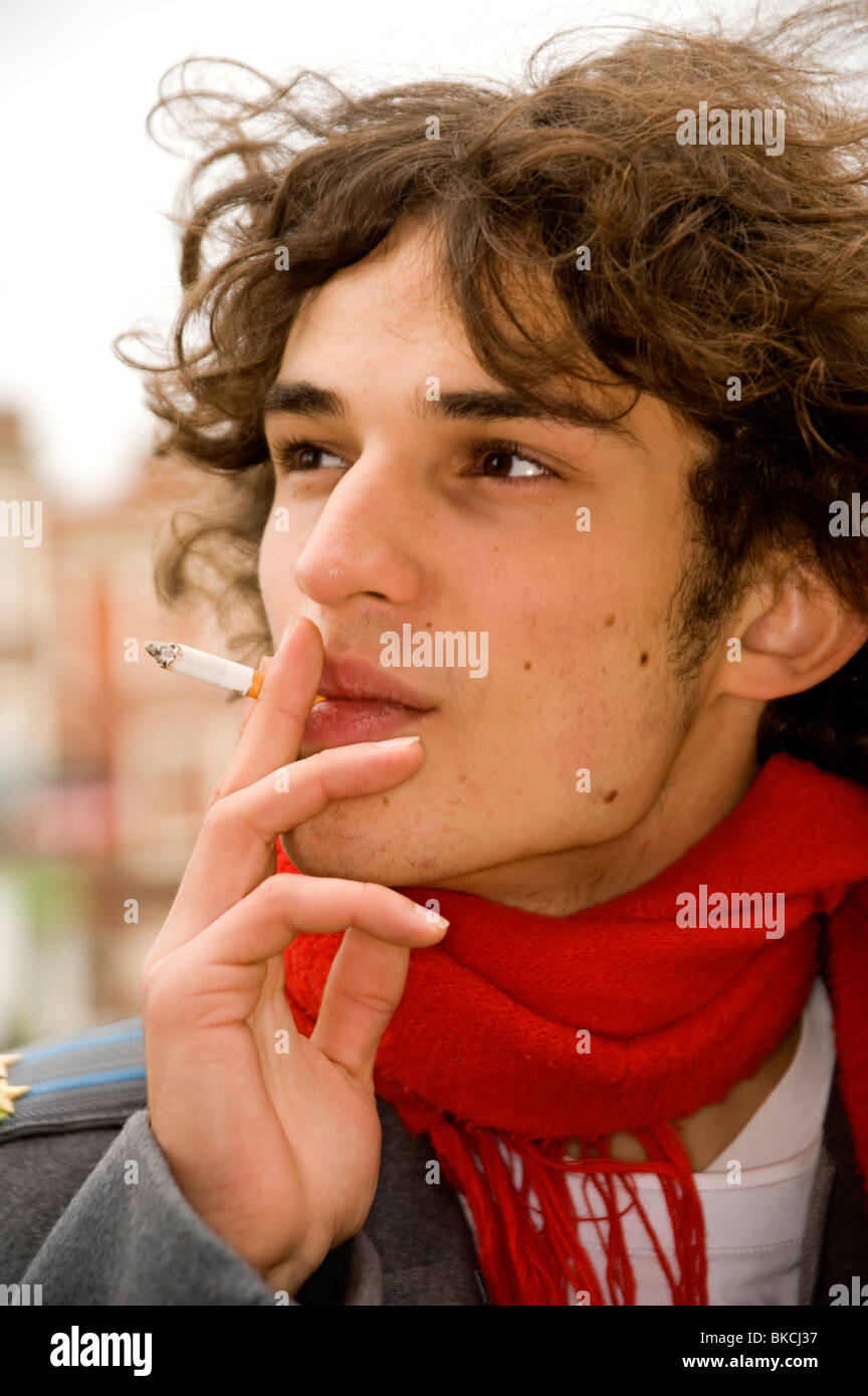 gut aussehende Teenager im Profil eine Zigarette rauchend Stockfoto