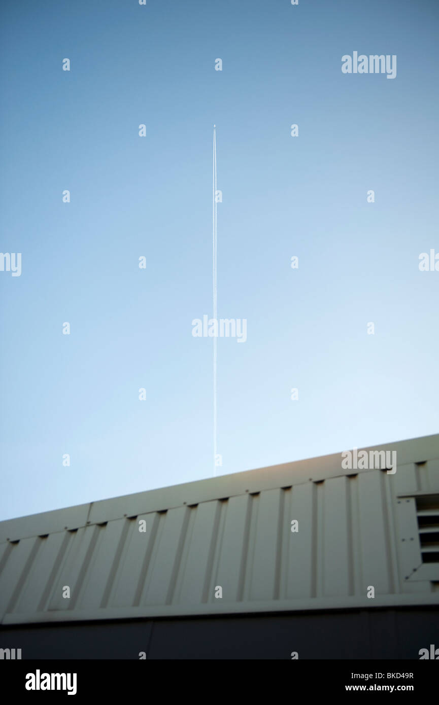 Flugzeug Jet Trail über Fabrik Bürogebäude Stockfoto