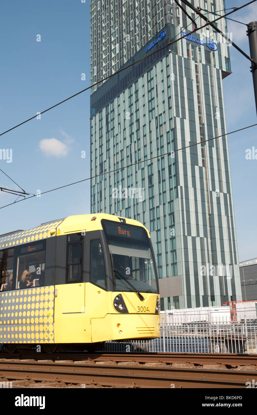 Metrolink Straßenbahn im Stadtzentrum von Manchester mit dem Hilton Hotel im Hintergrund. Stockfoto