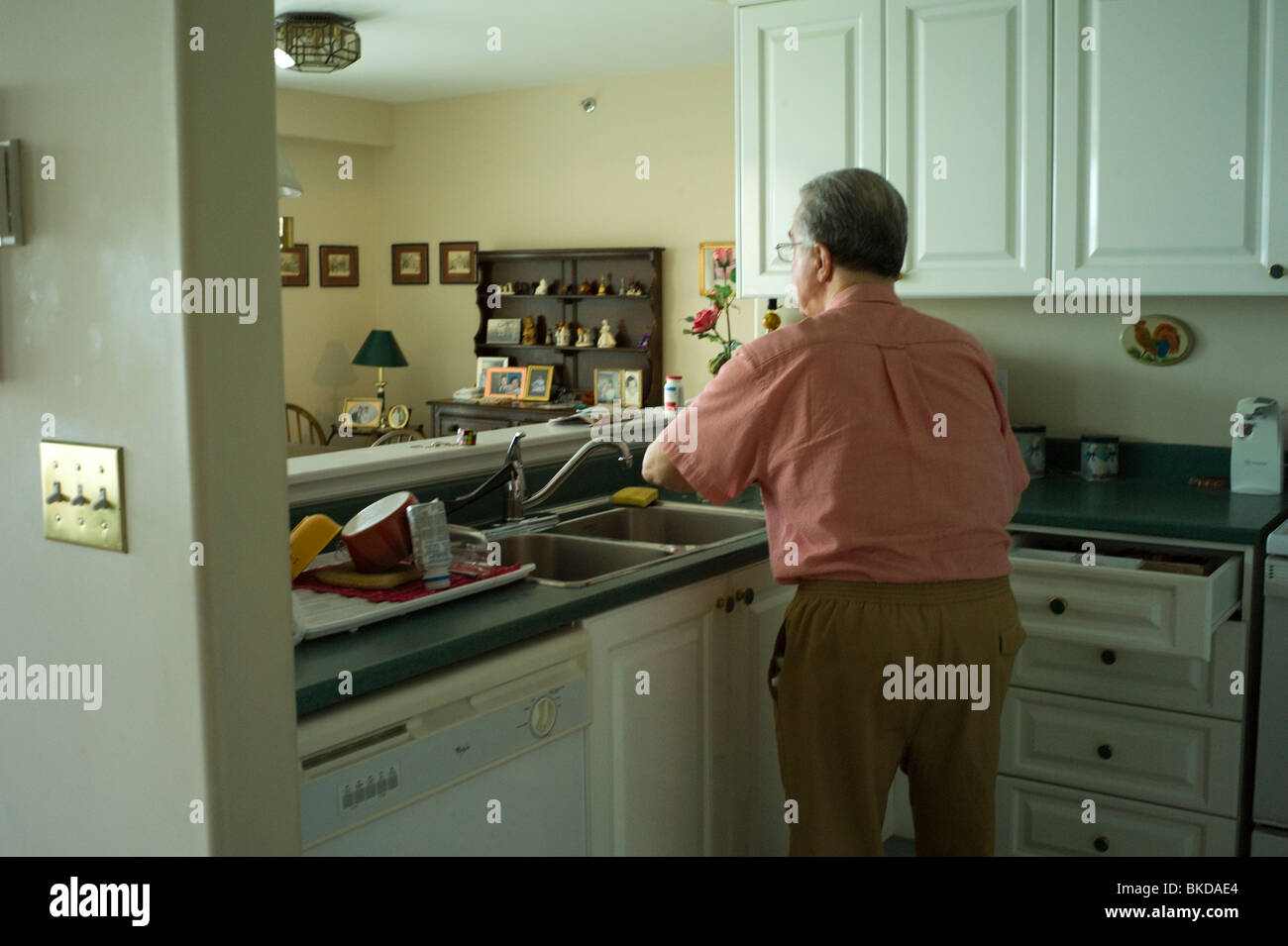 Alter Mann reinigt Geschirr im Spülbecken Stockfoto