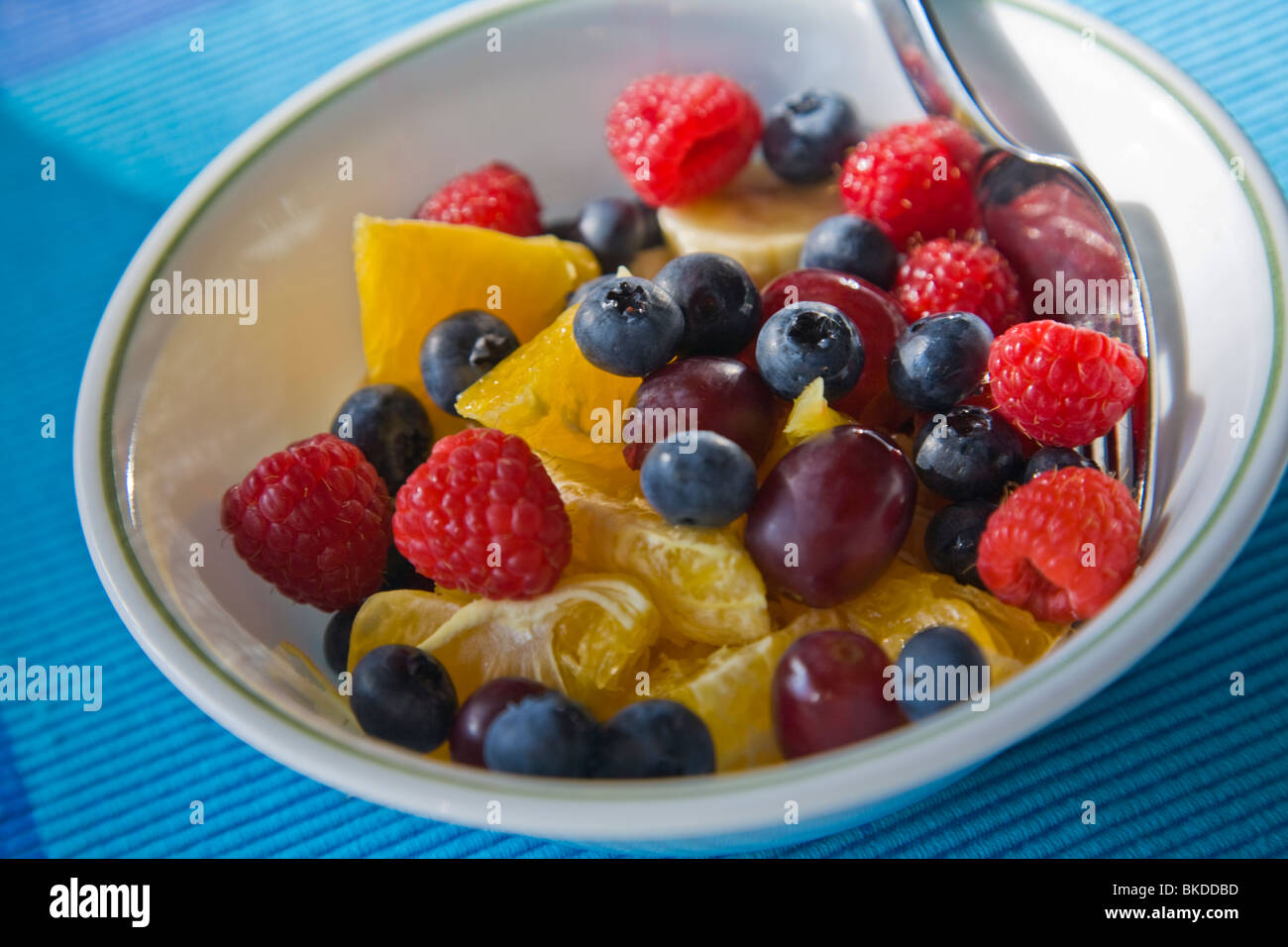 Nahaufnahme der Schüssel mit gemischten frischen Früchten mit Heidelbeeren Himbeeren Orangen Trauben und Bananen Stockfoto