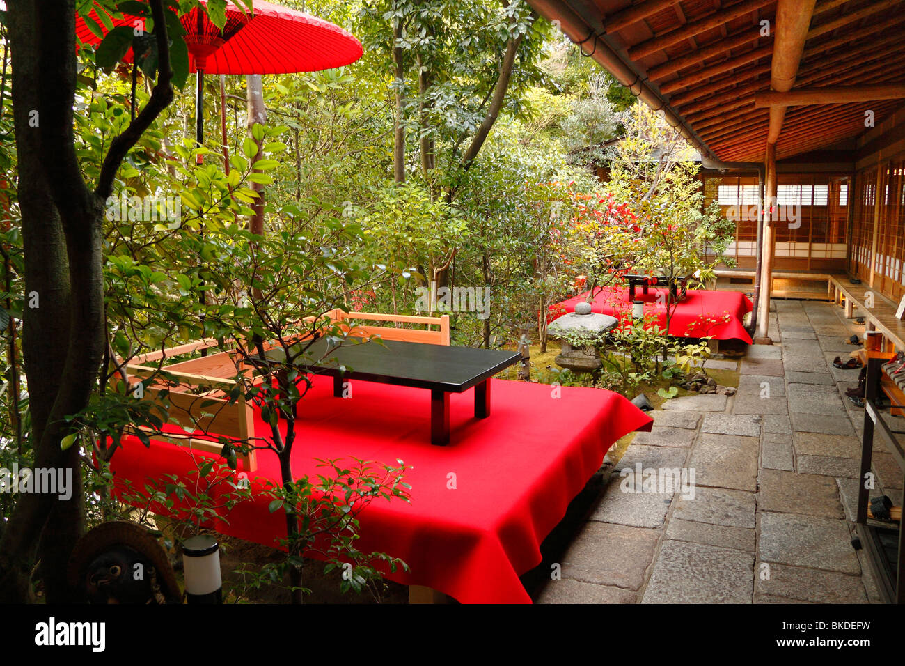 Traditionelle japanische Teehaus in Alleinlage des Kyoto-Protokolls mit rotem Tuch Tischen und Sitzbereich, umgeben von Bäumen Stockfoto