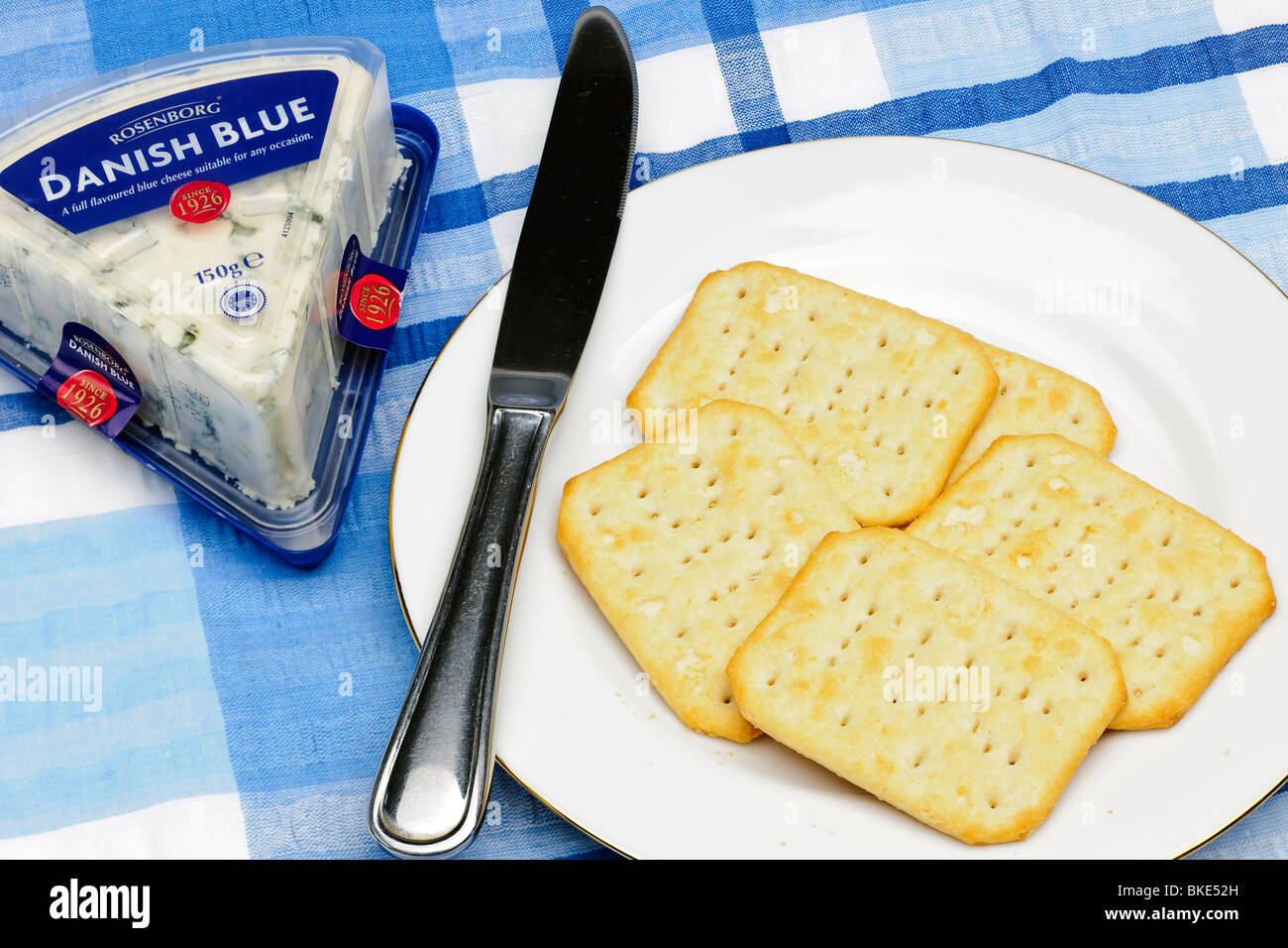 Fünf TUC Cracker auf einem weißen Teller mit einem Rudel von dänischen Blauschimmelkäse und Messer Stockfoto