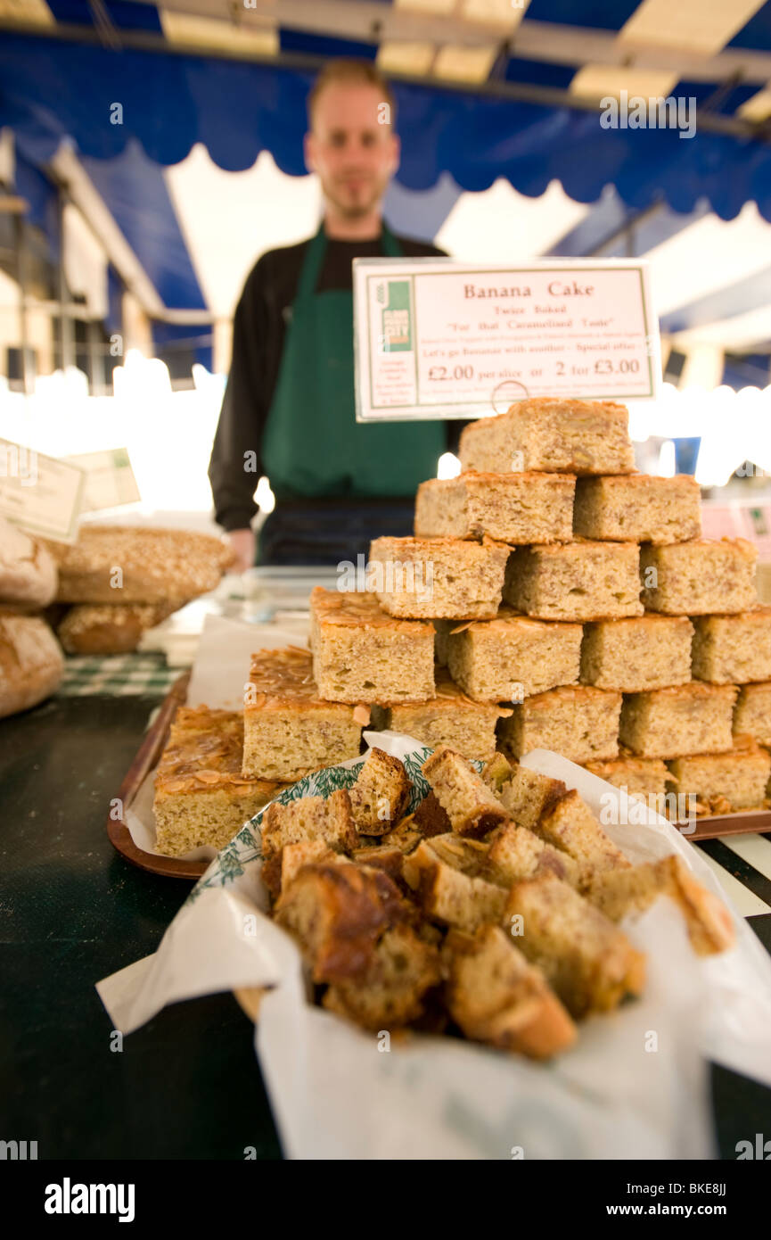 Markt-Stall-Inhaber bei Clapham Venn Street Market, In London, England, UK-Bananen-Kuchen zu verkaufen. Stockfoto