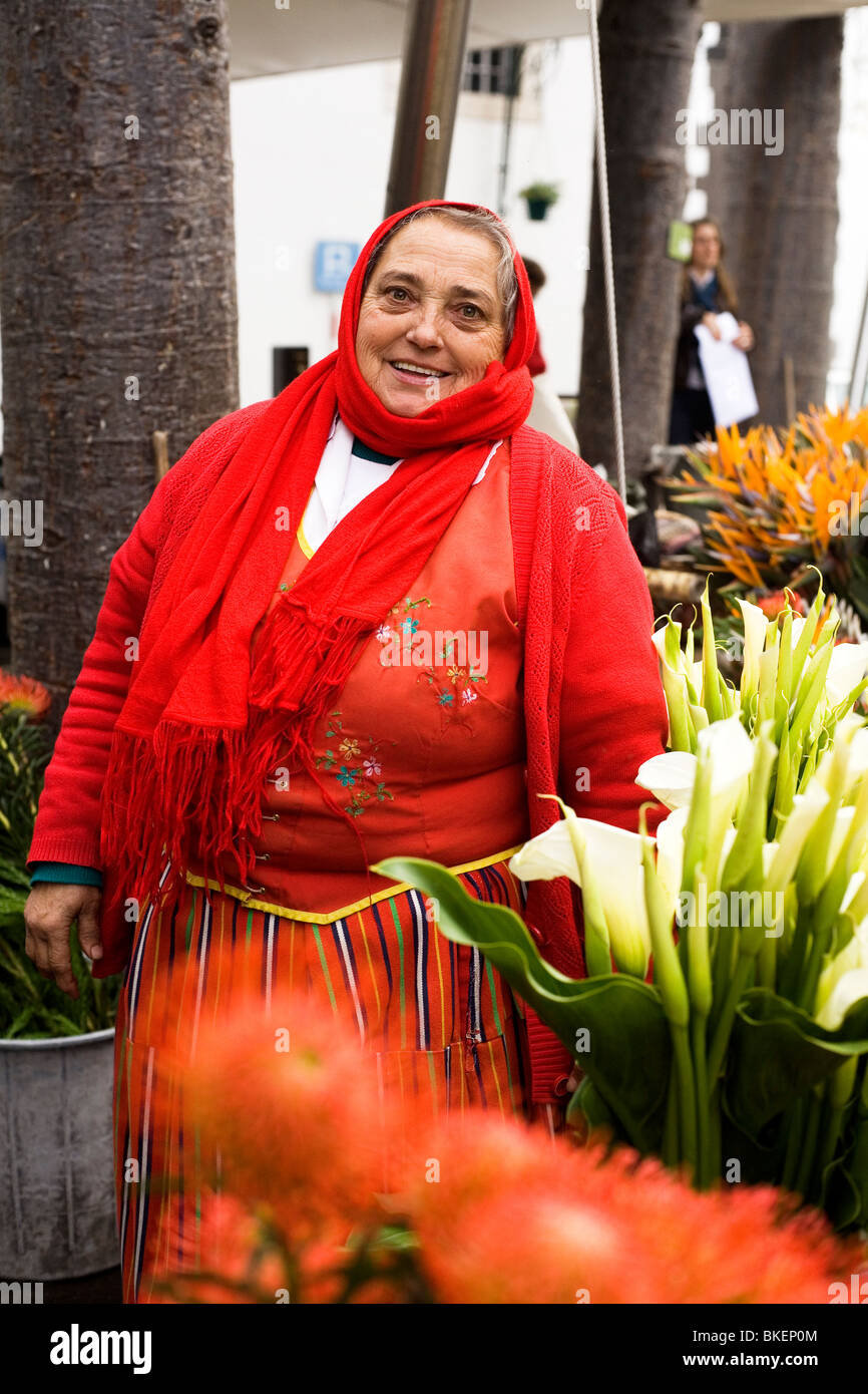 Eine Blumenverkäuferin Kleider in eine traditionelle rote madeirischen  Kostüm funktioniert einen Markt in der Hauptstadt Funchal, Madeira  Stockfotografie - Alamy