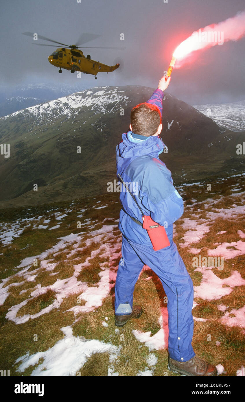 Mitglied Mountain Rescue verwendet eine Fackel, einen nahende Meerkönigs Hubschrauber auf die Unfall-Website, Lake District zu gewinnen Stockfoto