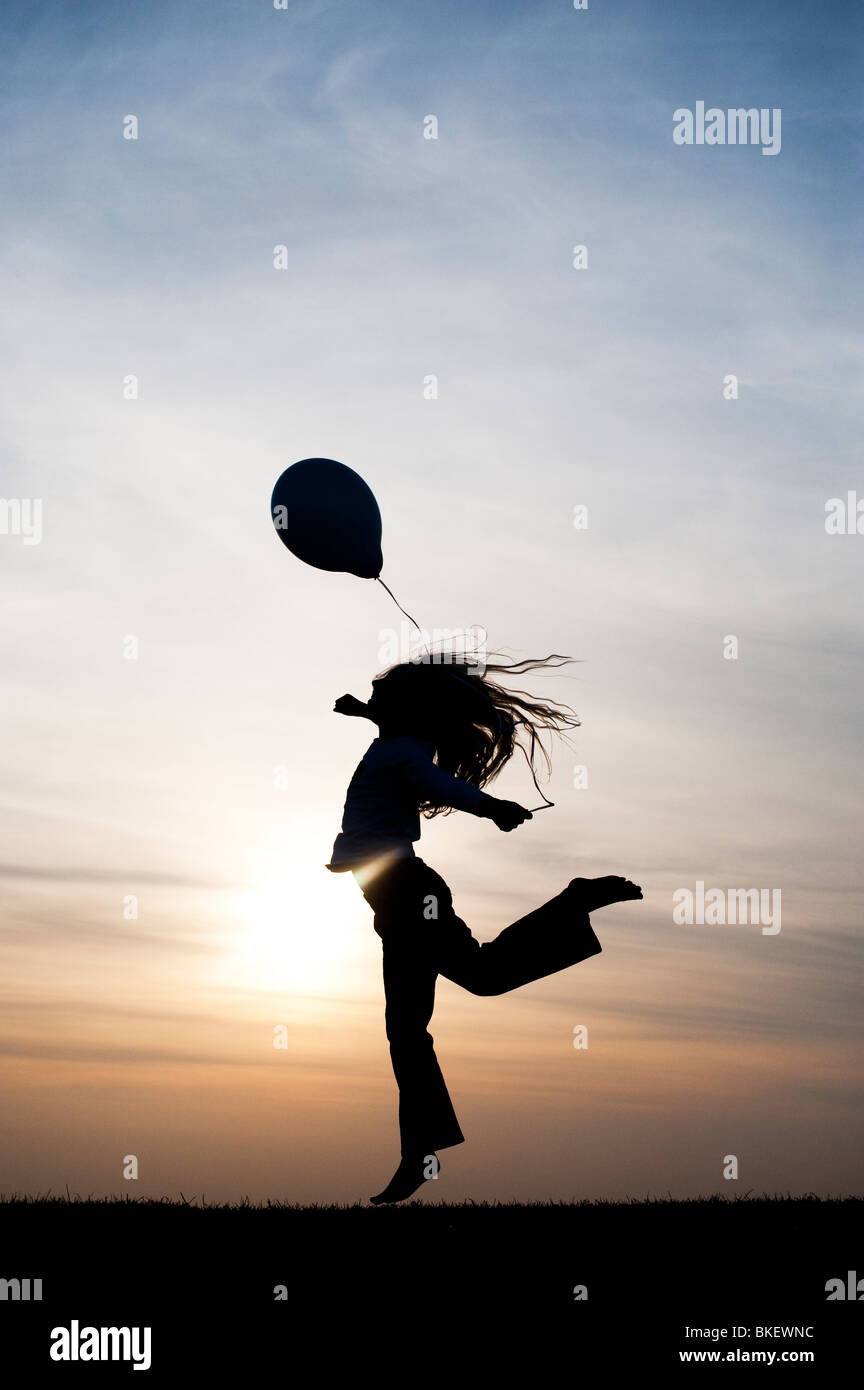 Silhouette eines jungen Mädchens, das Spielen mit einem Ballon bei Sonnenuntergang Stockfoto