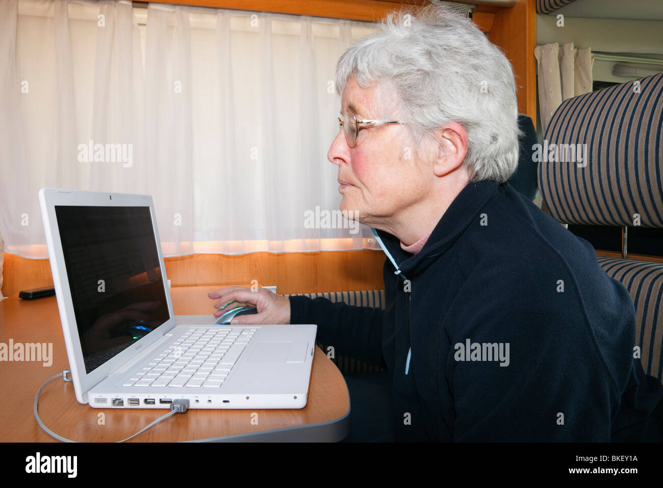 Ältere Frau Rentner mit WLAN auf einem MacBook Laptop in einem Reisemobil. England Großbritannien Großbritannien Stockfoto