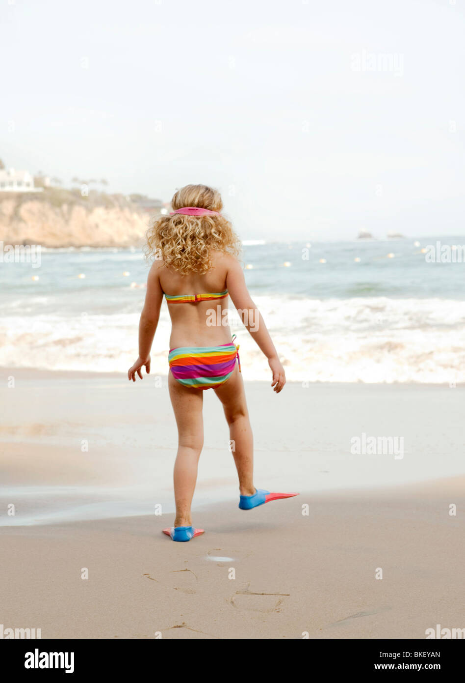 Mädchen in gestreiften Bikini und Flossen am Strand Stockfoto