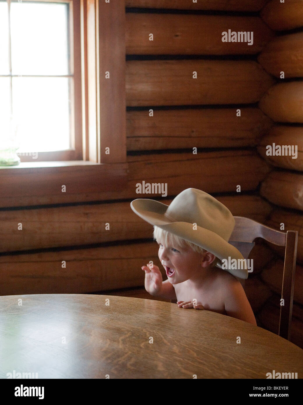 Junge am Tisch mit Cowboy-Hut Stockfoto