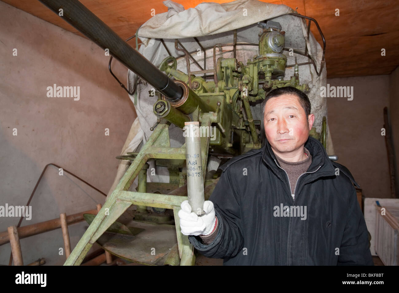 Ein chinesischer Arbeiter, deren Aufgabe es ist, feuern Granaten, gefüllt mit Silberjodid in die Wolken zu versuchen und es regnet. Stockfoto