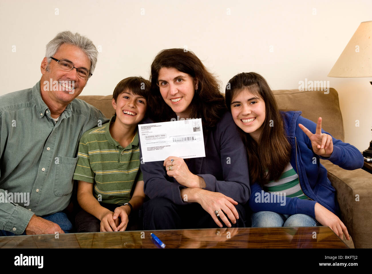Weiße vierköpfige Familie Lächeln für die Kamera mit der Volkszählung 2010 in einem Mailing-Umschlag, Eltern mit ihren jungen 11 und 13 Mädchen. Stockfoto