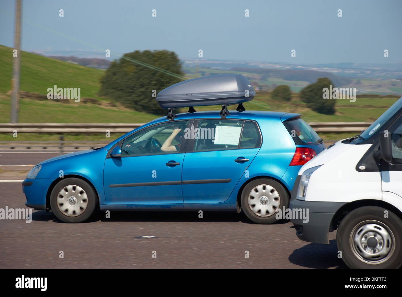 Blauer VW Golf mit Dach-Boot auf der Autobahn M62 (in der Nähe von Outlane, Huddersfield). Stockfoto