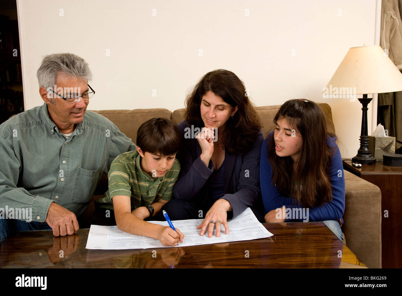 Familie von vier gerade während ihrer 11-jährigen Sohn seinen Anteil von der Volkszählung 2010, 13-jährige Schwester füllt auch Uhren. Stockfoto