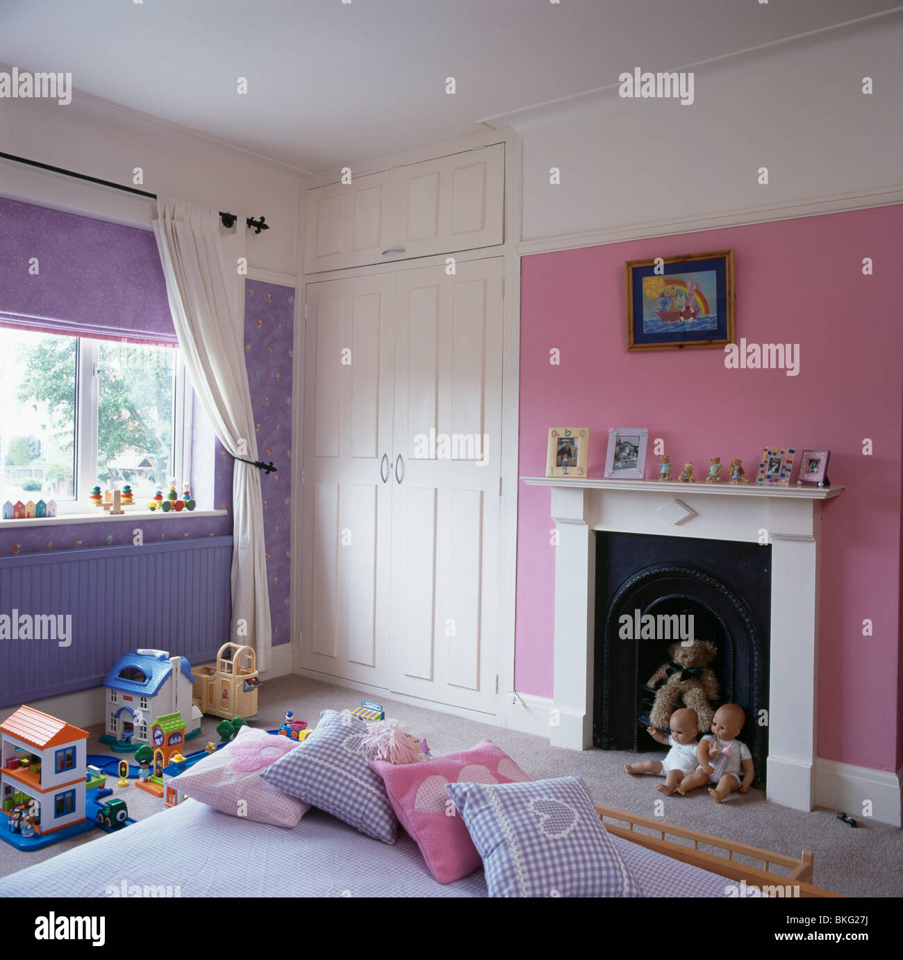 Rosa und lila Kinderzimmer mit weißer Einbauschrank und weißen Kamin  Stockfotografie - Alamy