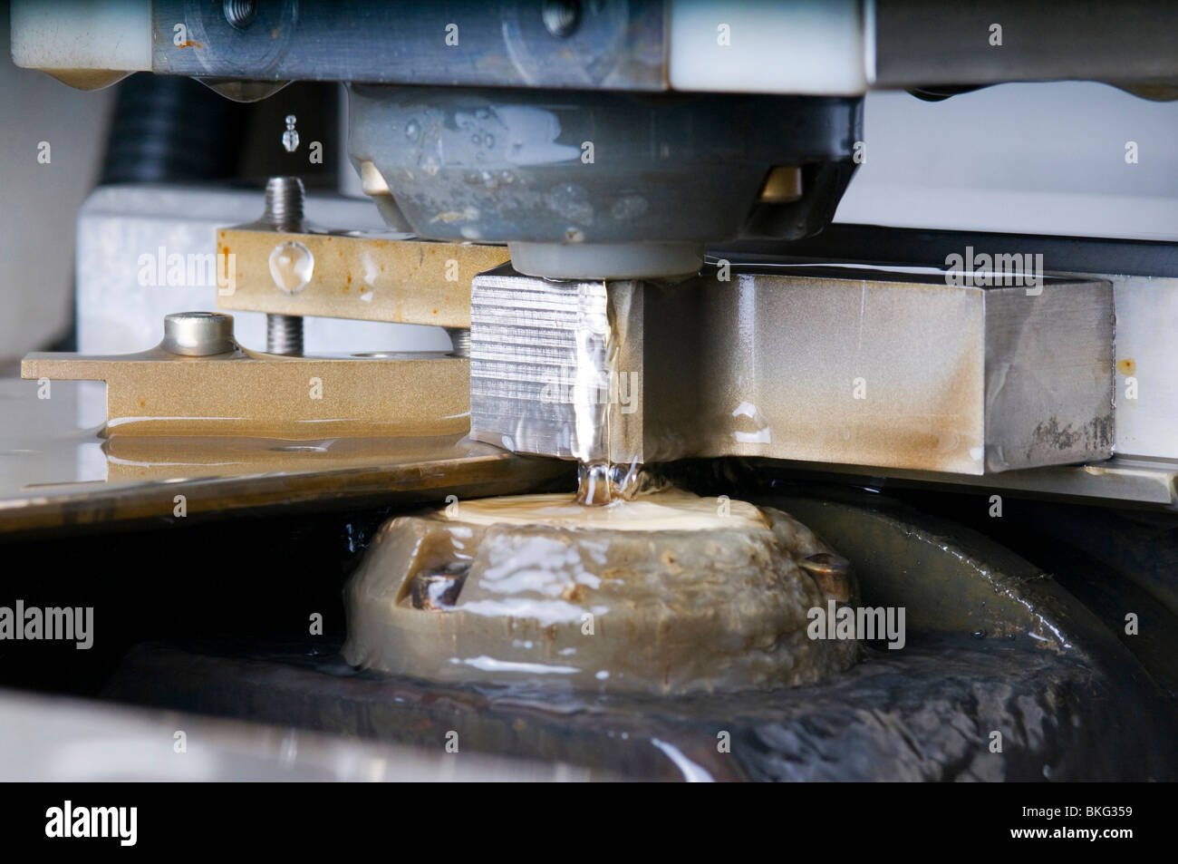 Nahaufnahme von einem Draht-Erodiermaschine Gestaltung ein Stück Metall mit Wasserkühlung eingeschaltet. Stockfoto