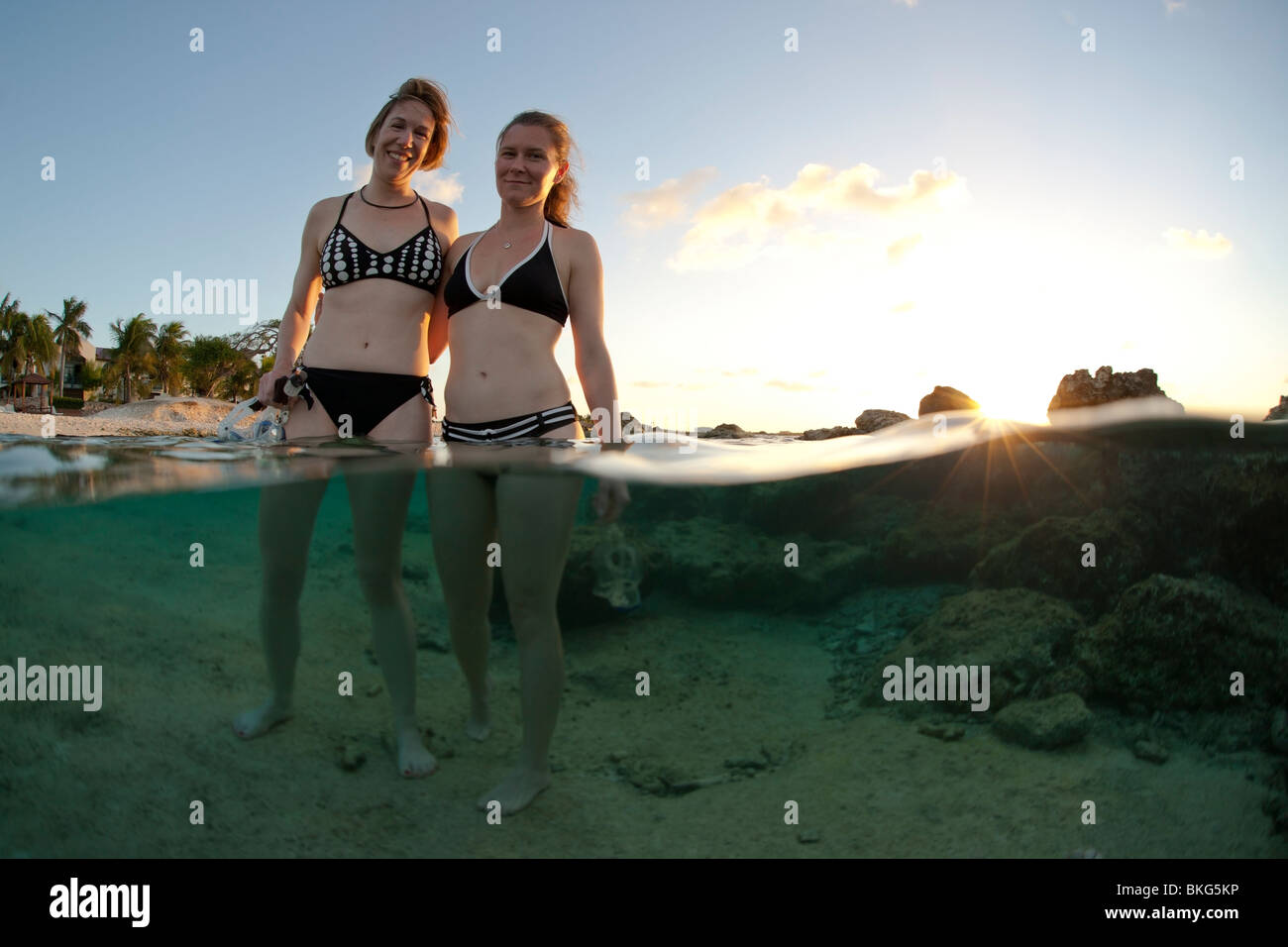 Unter und über Bild von Schnorchler waten im Wasser im Plaza Resort in Bonaire, Niederländische Antillen bei Sonnenuntergang. Stockfoto