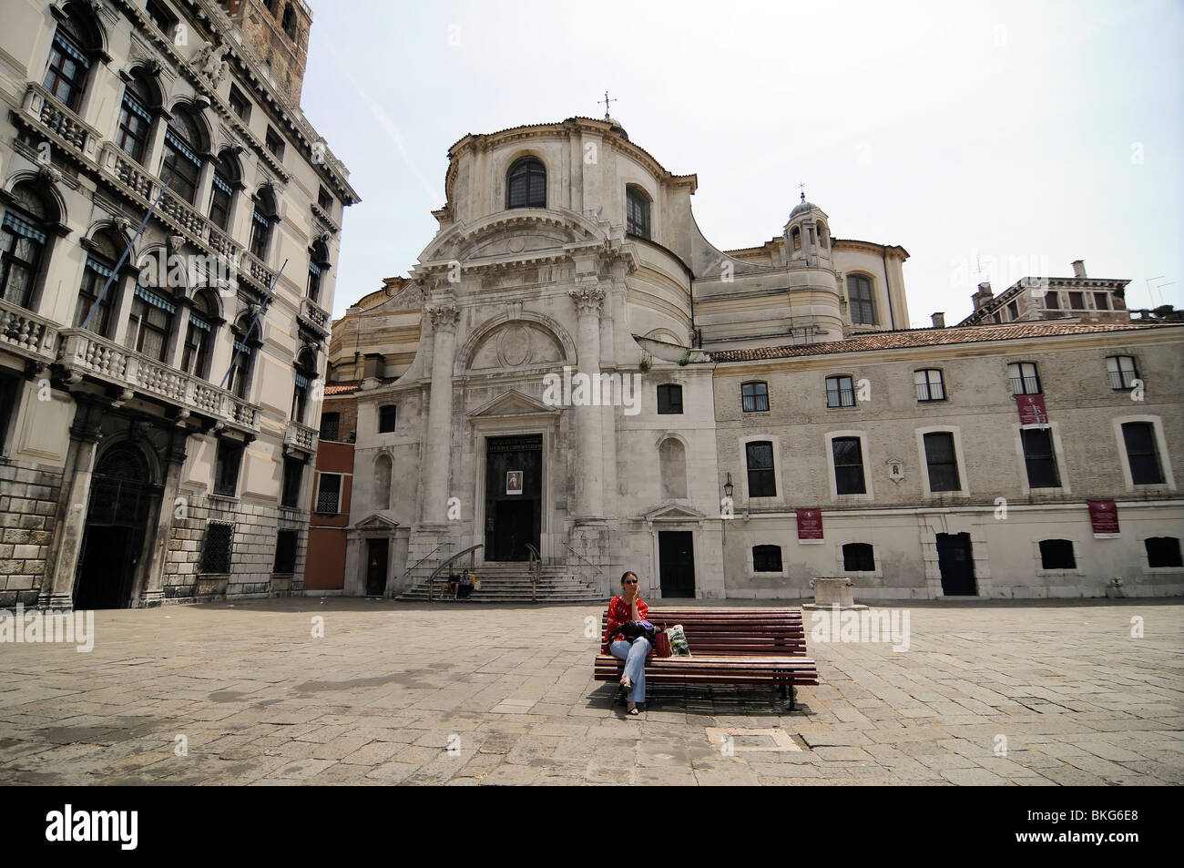 Eine Dame sitzt auf einer Bank auf einem Platz in Venedig (Italien) Stockfoto