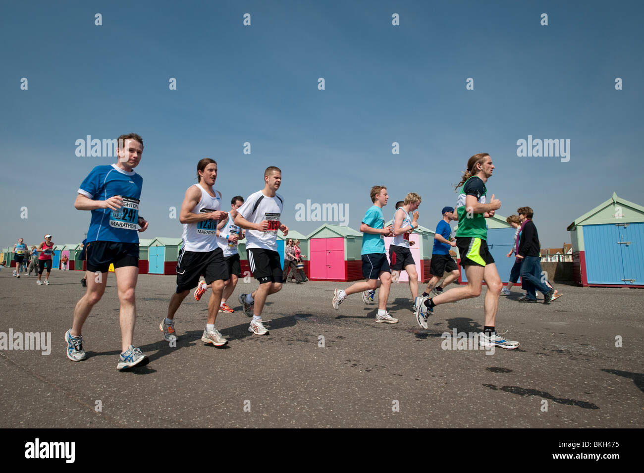 Läufer passieren bunt bemalte Strandhütten in Hove während den letzten paar Meilen von Brighton Marathon Stockfoto