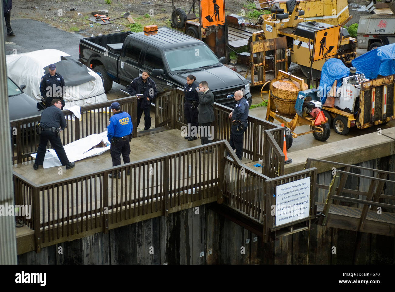 NYPD Offiziere warten auf die Ankunft des Untersuchungsrichters nach dem Entfernen einer Leiche in den verschmutzten Gewässern der Newtown Creek in New York Stockfoto