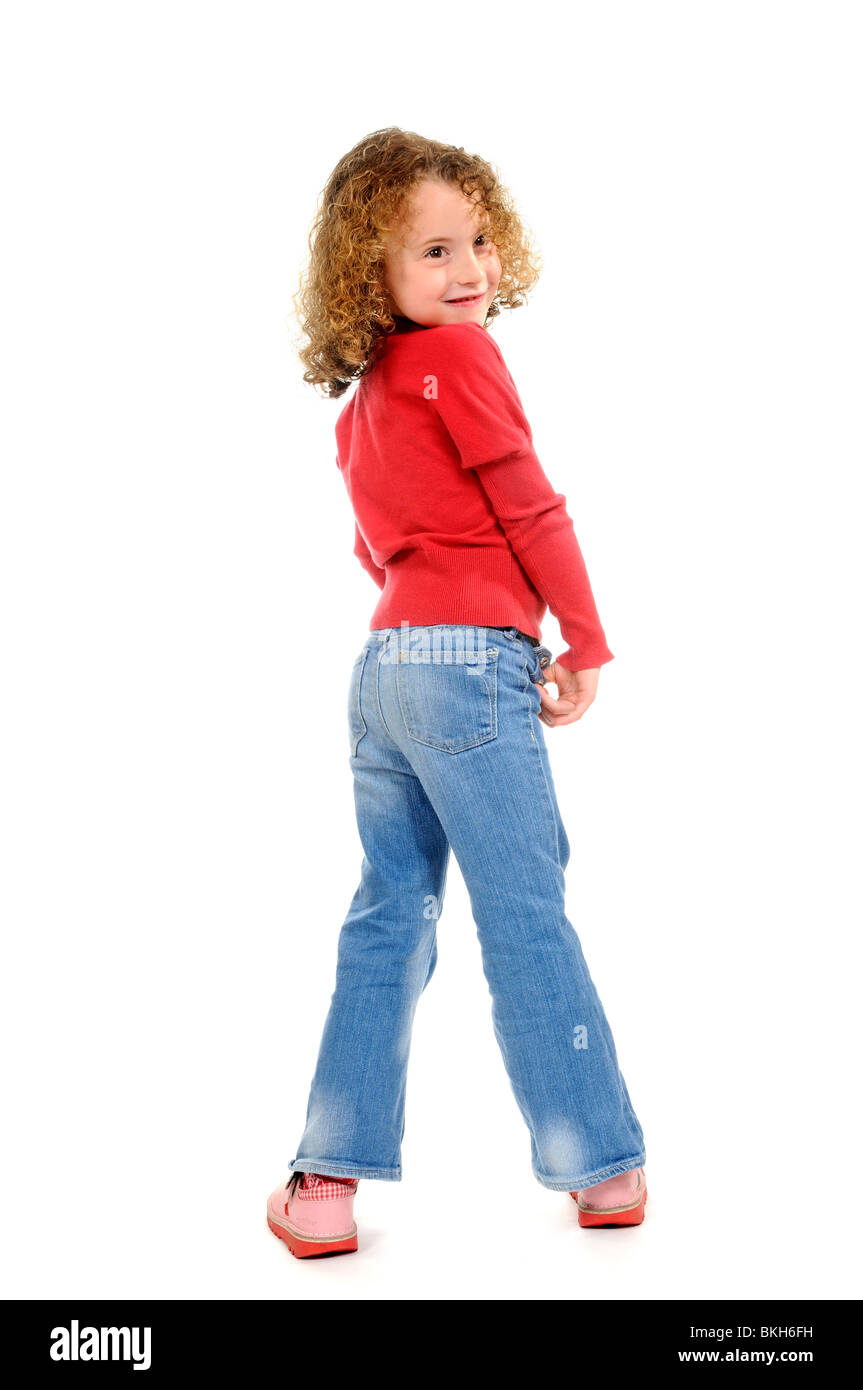 Sechs Jahre altes Mädchen mit einer losen Schneidezahn tragen blaue Jeans & ein rotes Hemd mit Sandalen posiert für die Kamera Stockfoto