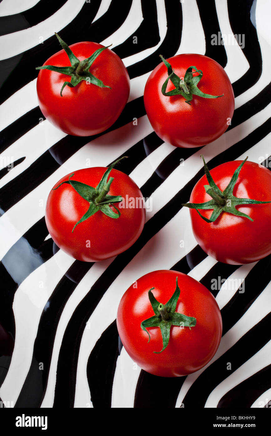 5 Tomaten auf gestreiften Teller Stockfoto