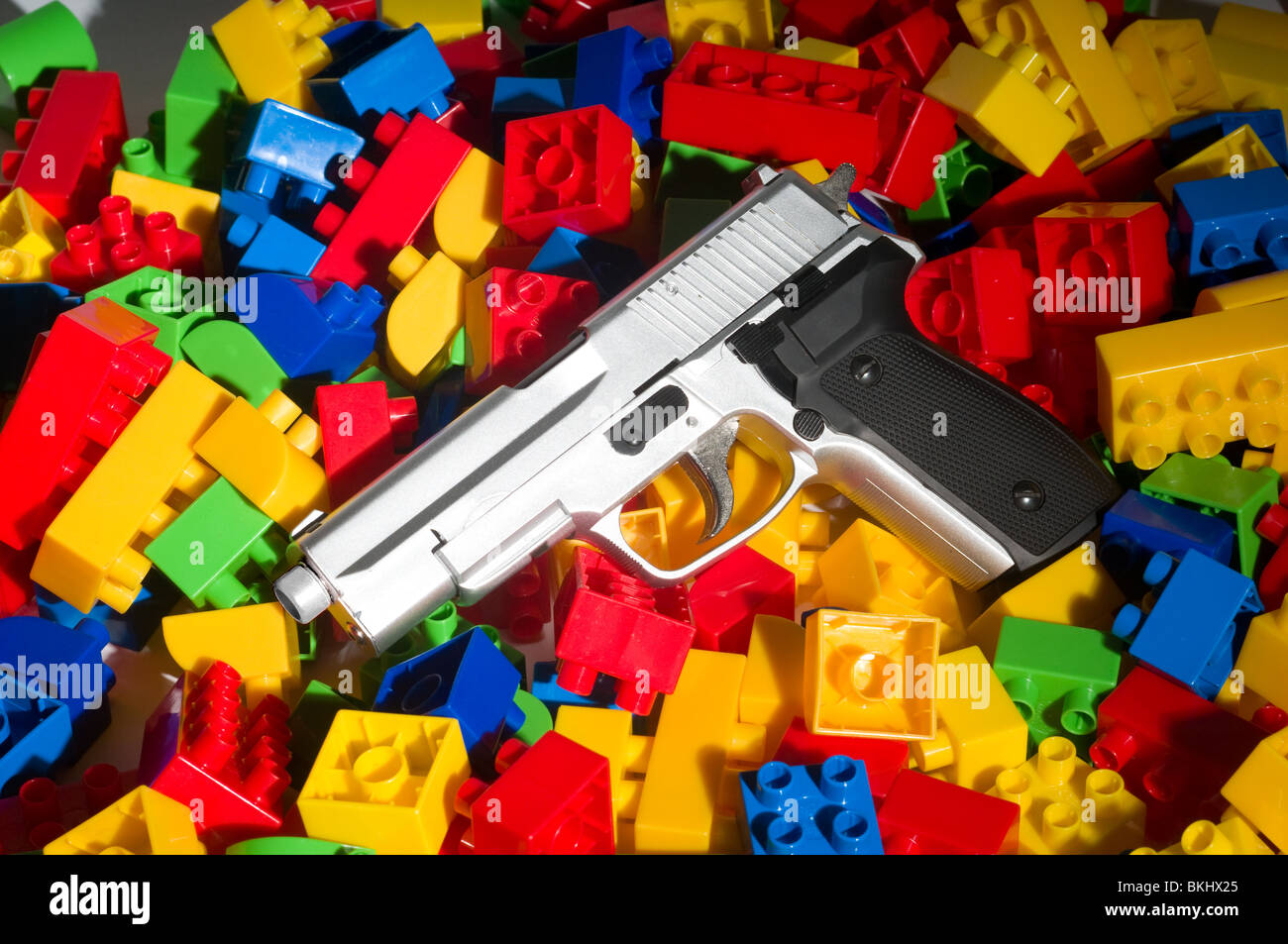 Pistole auf einen Haufen von Kunststoff Bausteine des Kindes. Stockfoto