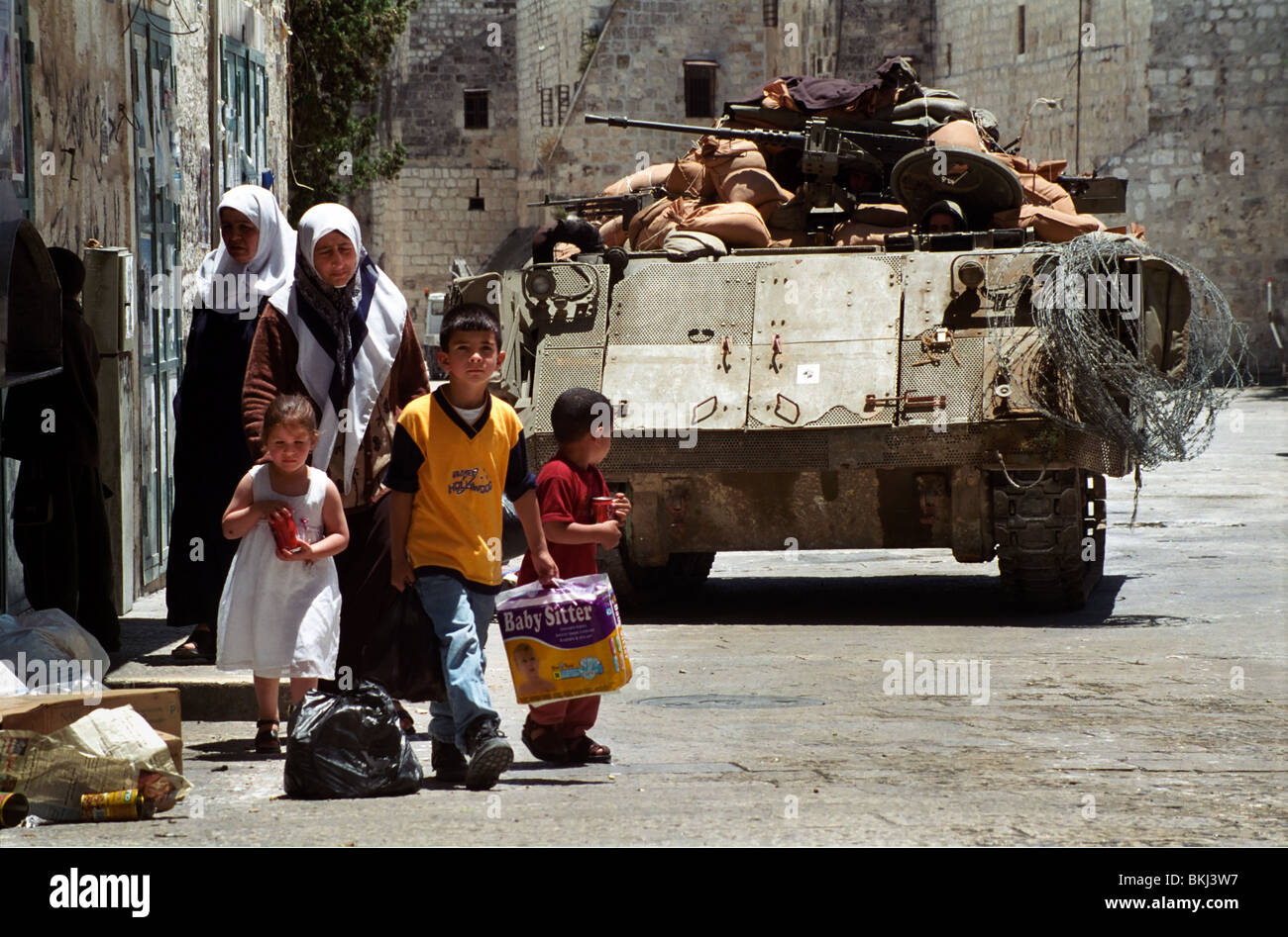 Palästinensischen Bewohner von Bethlehem Fuß in der Nähe von einem israelischen Panzer bewacht Krippenplatz während einer Pause in einem israelischen militärischen Ausgangssperre. Stockfoto