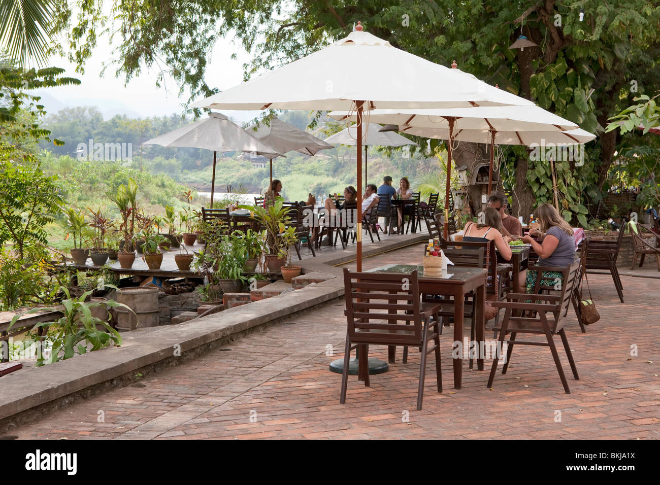 Junge Touristen genießen das Nan Flussufer in eines der vielen Restaurants im Freien am Flussufer in Luang Prabang, Laos Stockfoto