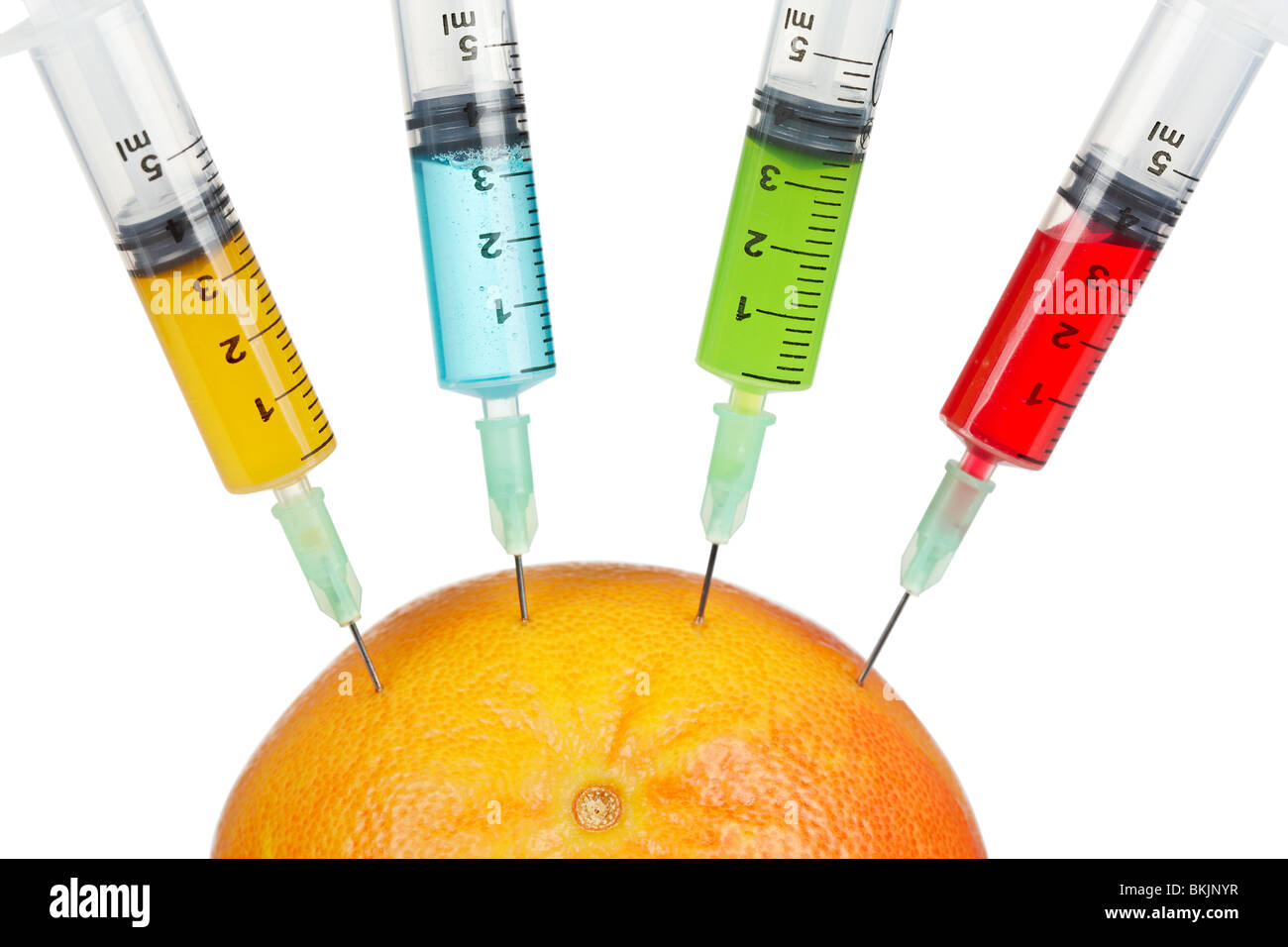 Eine Grapefruit mit vier Spritzen mit Farbe Flüssigkeiten, isoliert auf weißem Hintergrund injiziert werden. Geringe Schärfentiefe Stockfoto