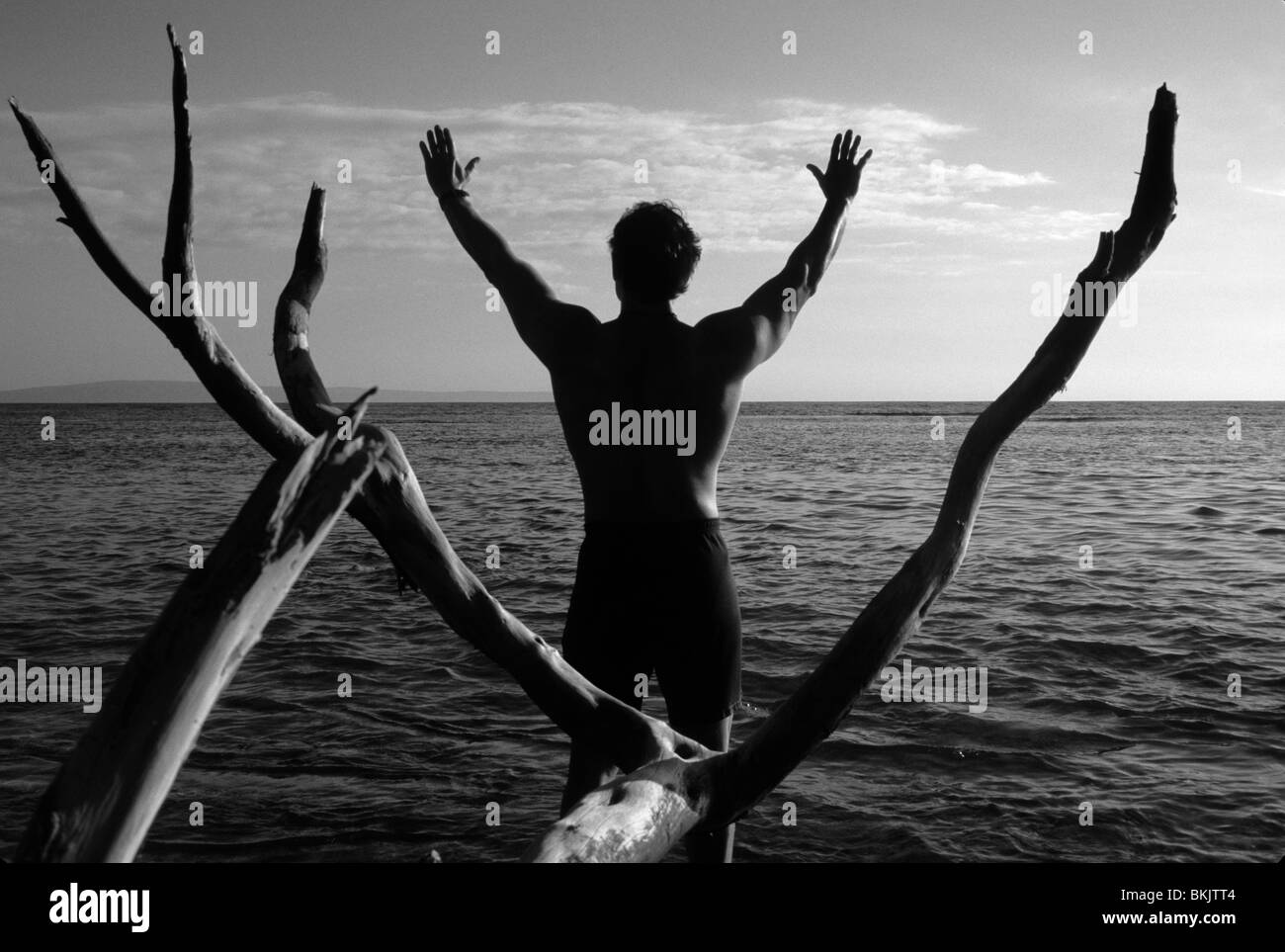 Menschen praktizieren Yoga mit erhobenen Armen, außen am Rand des Wassers, schwarz / weiß Stockfoto